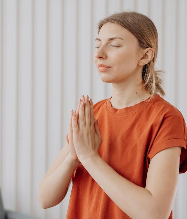 Woman in a calm yoga pose in a beautifully lit room.